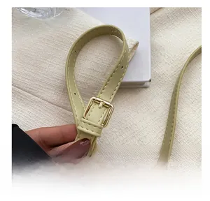 Detail of light green leather strap with gold hardware buckle and neat stitching