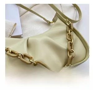 Detail of avocado green dumpling bag featuring ruched leather texture and acrylic chain strap
