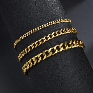Ensemble de trois bracelets gourmettes dorés en acier titane sur support noir