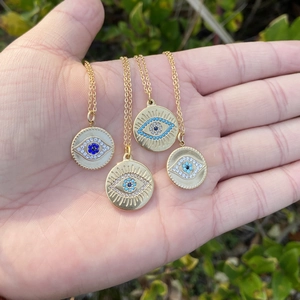 Détail de quatre colliers avec pendentif œil maléfique doré aux textures radiales