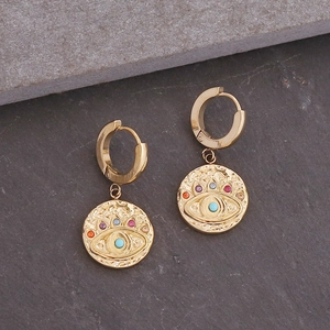 Detailopname van gouden oorringen met boze oog hanger en kleurrijke stenen op stenen basis