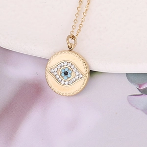 Collier avec pendentif disque Mauvais Œil doré orné de cristaux et perle centrale bleue