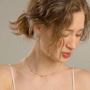 Détail d'un collier en titane doré porté avec trois pendentifs en zircon carrés