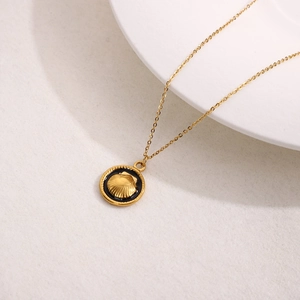 Golden stainless steel necklace with round shell pendant on white textured background