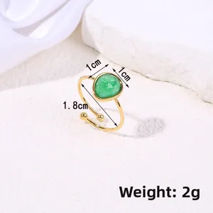 Adjustable gold ring with drop-shaped green natural stone on white marble background
