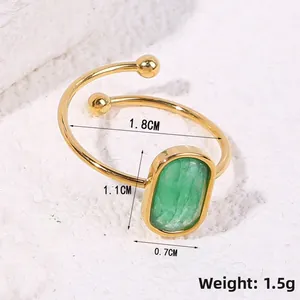 Macro shot of gold adjustable ring with a green rectangular gemstone on stone background