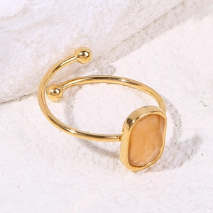 Detailed top view of a gold-plated adjustable ring with an oval yellow gemstone on marble