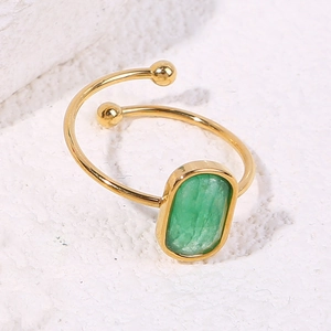 Macro detail of a green stone ring with double ball ends on a stone surface