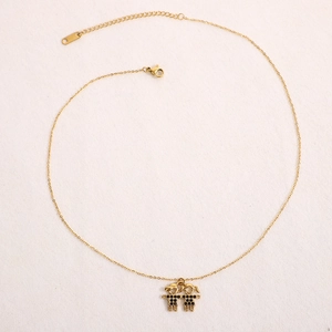 Détail macro d'un collier doré avec pendentifs garçon et fille sertis de diamants