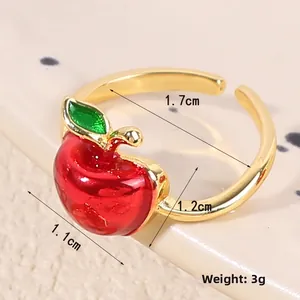 Macro d'une bague pomme rouge avec anneau doré ajustable et détail de feuille verte