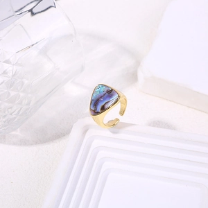 Close-up of golden triangle ring featuring iridescent abalone shell inlay on white stand