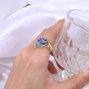 Detail of a geometric triangular abalone shell ring with polished gold finish on silk