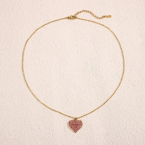 Dettaglio del ciondolo a cuore in cristallo rosa con catena d'oro e chiusura a moschettone