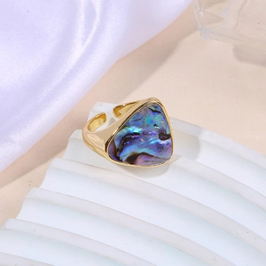 Golden geometric ring with triangle abalone shell on elegant silk background