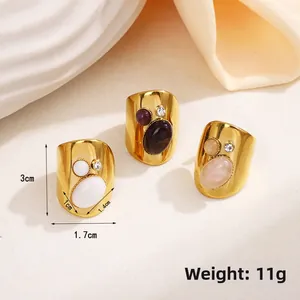Detail view of vintage wide rings with inlaid stones on white plate and silk fabric