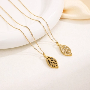 Elegant gold leaf necklaces with sparkling rhinestones on a white ceramic plate