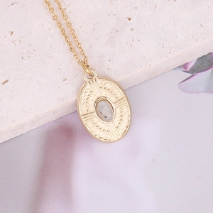 Vintage gold oval pendant necklace with a blue natural stone on a stone background