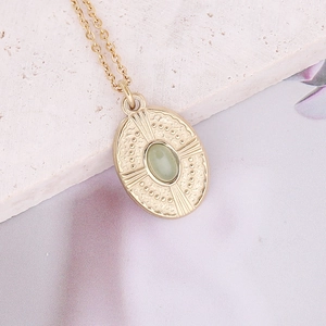 Vintage gold oval necklace with a light green stone inlay on a textured stone base