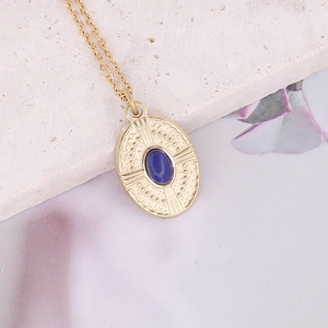 Macro view of vintage gold necklace with blue stone pendant and engraved sunburst texture
