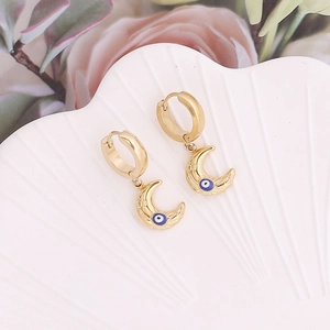 Macro de boucles d'oreilles lune dorées avec œil protecteur sur plateau en coquillage