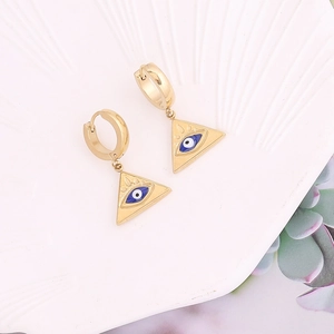 Gros plan détaillé de boucles d'oreilles œil bleu en triangle doré sur plateau en porcelaine