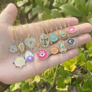 Close-up of golden necklaces with colorful boho charms like evil eye and moon