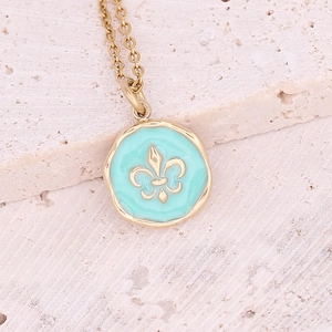 Macro view of a gold-plated necklace featuring a blue enamel fleur-de-lis pendant