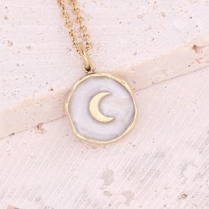 Macro detail of golden crescent moon pendant necklace with white starry shell inlay