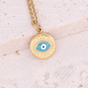 Macro detail of golden evil eye pendant necklace on a natural white stone background