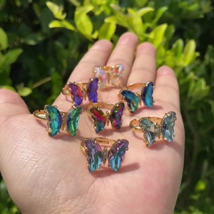 Close-up of butterfly ring set with colorful gradient wings on a golden band
