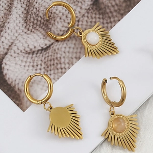 Detail view of golden hoop earrings with sunburst charms and inlaid round natural stones