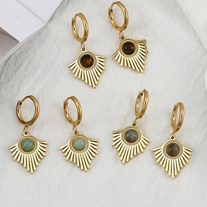 Detail of three pairs of vintage sunburst earrings with natural stone insets on white fabric