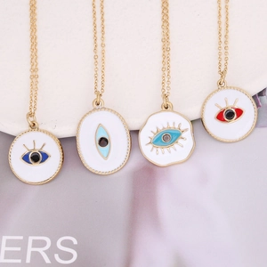 Colliers Evil Eye dorés avec émail blanc et pupilles colorées sur un plateau blanc