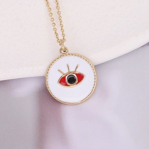 Gros plan du pendentif œil en émail blanc et or avec iris rouge sur satin
