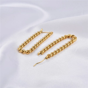 Minimalist gold rectangular twisted rope hoop earrings on white silk fabric