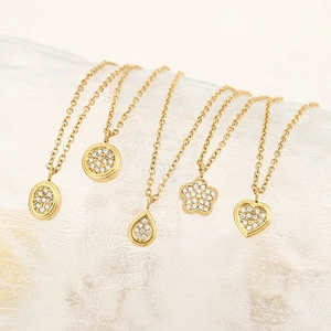 Dettagli di collane dorate con pendenti geometrici decorati con zirconi brillanti