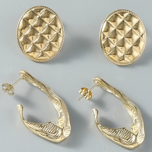 Vue détaillée des boucles d'oreilles dorées en titane avec textures matelassée et martelée