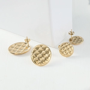 Détail de la texture matelassée dorée sur des boucles d'oreilles géométriques