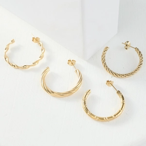 Set of four textured gold-plated geometric twist C-shaped hoop earrings on white blocks