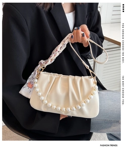 Detail view of a cream pleated cloud bag with pearl chain handle and floral scarf strap