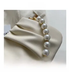 Detailed view of large white pearls and gold crystal beads on a cream shoulder bag