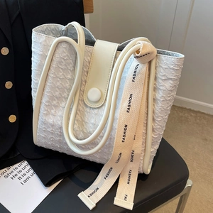 Large capacity white tote bag with textured fabric and fashion webbing strap on a seat