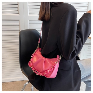 Pink pleated cloud bag with resin chain detail and leather strap shown on a black blazer