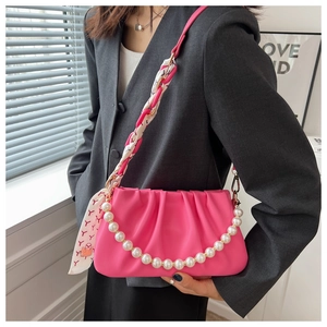 Detail of pink ruched cloud bag featuring pearl chain and red floral scarf strap