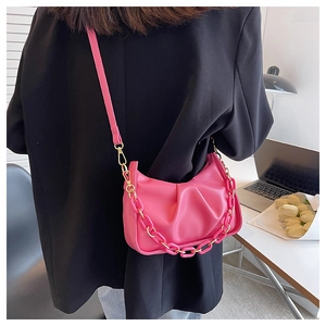 Detail of pink pleated cloud bag with acrylic resin and gold metal chain strap on model