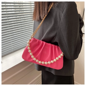 Detail of pink pleated handbag with large white faux pearls and gold chain strap