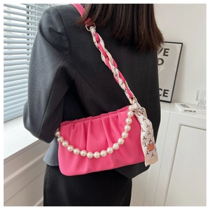 Detail of hot pink pleated bag with white pearl chain and silk scarf wrapped strap