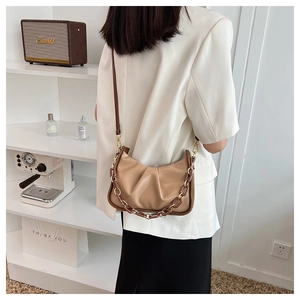 Chic beige pleated cloud bag with resin chain strap shown as a stylish underarm shoulder bag