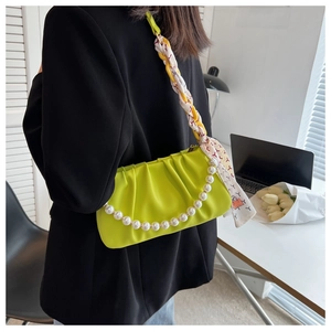Detail of neon green dumpling bag with pearl strap, resin chain and printed silk scarf