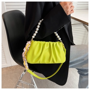 Detail of neon green pleated cloud bag with pearl handle and floral silk scarf decor